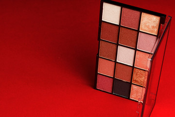 Makeup eyeshadow palette on the red background. Close up.
