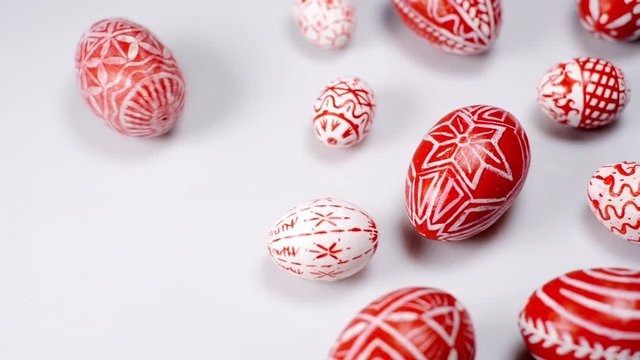 Red easter eggs with folk Ukrainian pattern lay around on white background. And man rotate one egg beside. Ukrainian traditional eggs pisanka and krashanka.
