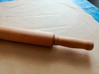 Wooden rolling pin on rolled dough.