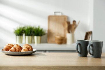 Wooden table in a sunny kitchen in the morning light during breakfast