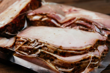 Smoked meat, sliced and packed in a vacuum package, closeup.