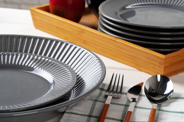 Glossy grey ceramic plate with cutlery on wooden kitchen table