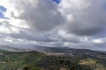 Rock volcanic formation and surrounding nature, capturing trees and shrubs moving in strong wind during a sunny afternoon with a blue sky in the valley area of the Gran Canary Island