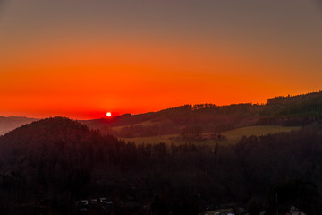 Close up sunset timelapse when sun is behind hills and mountains full of trees and moving clouds behind which sun sets a strong yellow-orange color view of the surrounding nature Beskydy Mountains