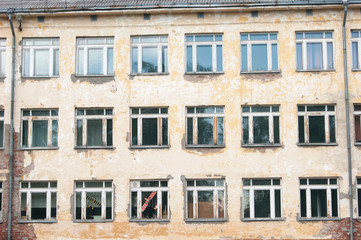 Decorative background - wall, windows. The photo shows the orange wall of the old school and many windows, in one of which a toy airplane is visible in red