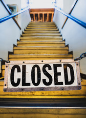 Metal sign with the words "closed" hanging across stairyway during time of Coronavirus Covid-19 pandemic