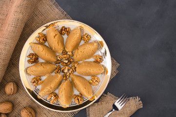 Fototapeta na wymiar Turkish famous traditional homemade flour halva served with walnut in plate on rustic background, turkish dessert for holy night or funeral