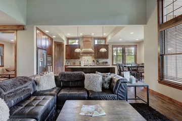 Luxury cozy living room interior with grey stone and rich wood with fuzzy blankets and open to kitchen.