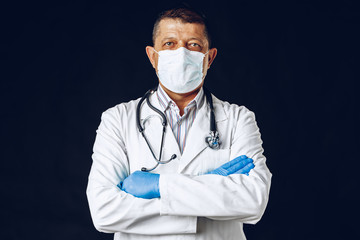 Elderly doctor with a medical face mask isolated on blue background. Close up.