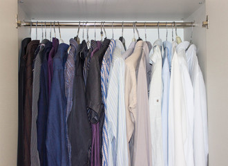 clothes and colored shirts hanging on rack in wardrobe. Concept of fashion
