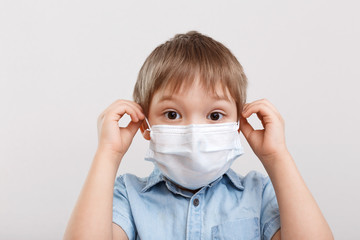 Little boy in a medical mask on a white background. Coronavirus concept. The child protects his health.