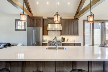 Amazing modern and rustic luxury kitchen with vaulted ceiling and wooden beams, long island with white quarts countertop.