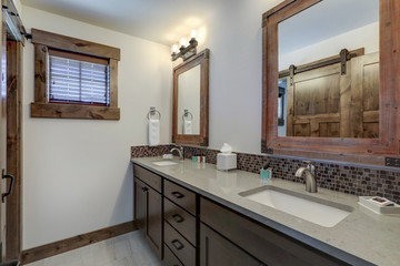 Bathroom interior with grey quarts countertop, two mirrors and barn style doors.