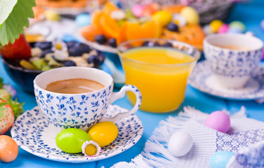 Easter breakfast. Fresh aromatic espresso coffee and easter colored eggs on a blue wooden background. Muesli, strawberries for breakfast.