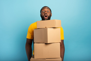 Man receives a lot of packages and has a surprised expression. Cyan background