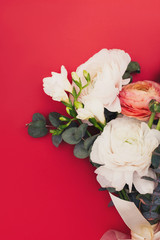 A cut view of bride bouquet of flowers on red background. Tulip, eucalyptus branches, Ausin roses and ranunculus. Flat lay