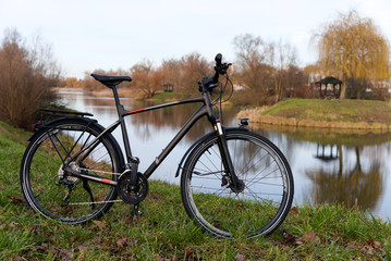 A new tourist bike standing on the shore of the lake. - obrazy, fototapety, plakaty