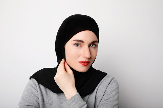 Muslim young woman wearing a black head scarf and smilling. Isolated.