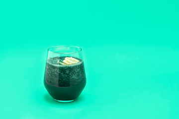 Vegan superfood spirulina smoothie with banana on light green background