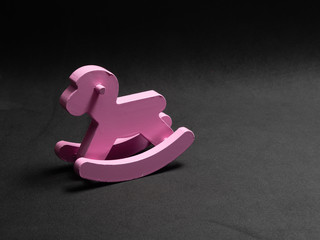 wooden pink horse rocker on black background