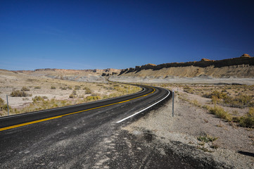Empty road under the cliffs in desert valley 