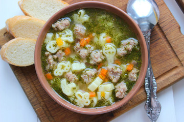 Hot soup, broth with meatballs, carrots, macaroni and fresh herbs.Delicious lunch on a wooden Board. Children's food, macaroni soup in the form of an airplane and a car.