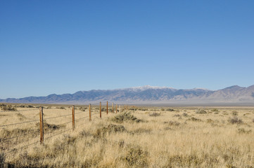 Fence running through grassland towards the mountains on the horizon