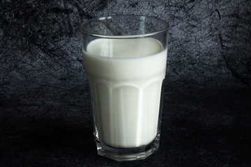 Glass transparent Cup of cow's milk close up on a grey textural background with copy space