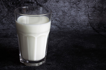 Glass transparent Cup of cow's milk close up on a grey textural background with copy space