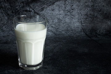 Glass transparent Cup of cow's milk close up on a grey textural background with copy space
