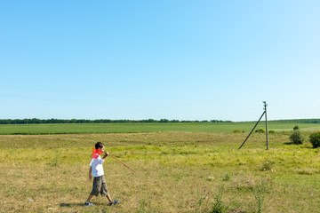 Young boy walkes in a clear  field on a summer day. He catches butterflies or insects with a butterfly net. Happy childhood concept