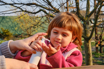 cute little girl daughter applying antiseptic alcohol gel on her hands.
