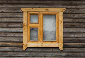 one side of a wooden house with a wooden window