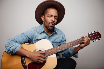 Happy bearded black man playing guitar and singing songs isolated on white background.