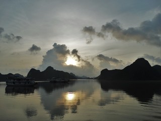 Sunset, mountains and boat reflection on the water in Ha Long Bay in Vietnam