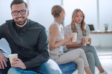 young businessman with a Cup of coffee sitting in a modern office.