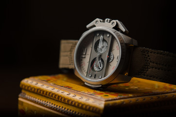 Retro steel watch with leather strap on wooden box.