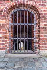Fototapeta na wymiar A steel grid door in a brick wall leading down to a hallway.