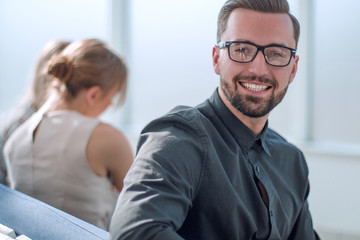 young businessman with a Cup of coffee sitting in a modern office.