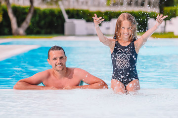 Fototapeta na wymiar Family of mom and little daughter enjoying summer vacation in luxury swimming pool