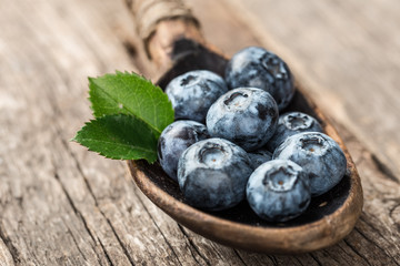 Blueberries in wooden spoon on old wood table. Healthy eating and nutrition concept.