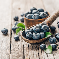 Blueberries in wooden spoon on old wood table. Healthy eating and nutrition concept.