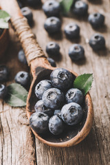 Blueberries in wooden spoon on old wood table. Healthy eating and nutrition concept.