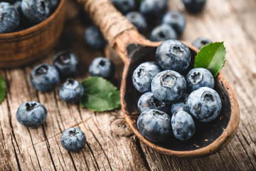 Blueberries in wooden spoon on old wood table. Healthy eating and nutrition concept.