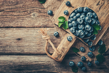 Freshly picked blueberries in bowl on wooden background. Healthy eating and nutrition.