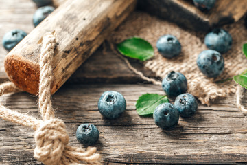 Freshly picked blueberries in bowl on wooden background. Healthy eating and nutrition.