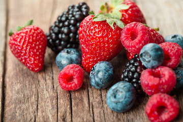 Fresh Summer Berries mix with Strawberry, Raspberry, Red currant, Blueberry and Blackberry on wood background.