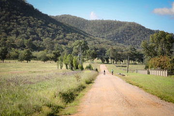 Two boys riding bikes on rural country road near Mudgee New South Wales