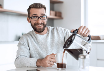 attractive man pouring himself a Cup of morning coffee