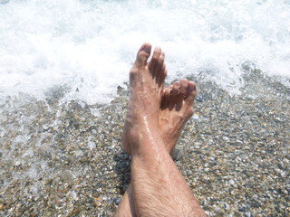 Feet in the water on the beach shore
